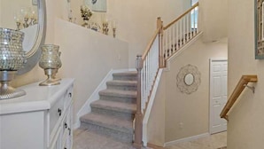 A staircase with a wooden handrail and a white wall with a decorative mirror and wall art. - Resort Style 3 Bed/2 Bath Garage Home in GATED River Strand Golf & Country Club! (Bradenton)