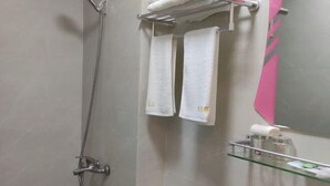 A bathroom with a shower, two towels hanging on a rack, a glass shelf with toiletries, and a toilet. - Xiangfu Hotel (Shanghai Guoding Road) (Shanghai)