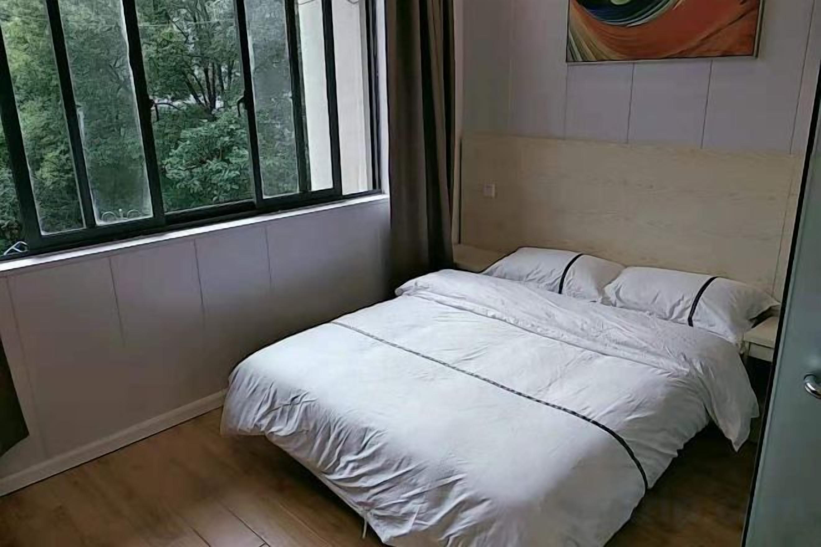 Un dormitorio con cama, ventana y un cuadro en la pared.