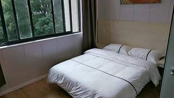 Un dormitorio con cama, ventana y un cuadro en la pared.