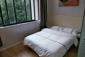 A bedroom with a bed, a window, and a painting on the wall. - Xiangfu Hotel (Shanghai Guoding Road) (Shanghai)