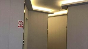 A hotel hallway with closed doors, a no-smoking sign, and a ceiling light. - Xiangfu Hotel (Shanghai Guoding Road) (Shanghai)