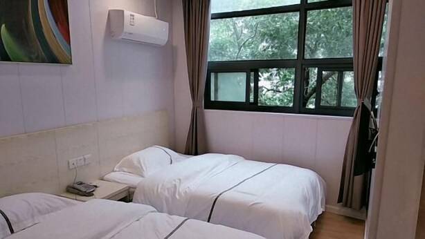A hotel room with two beds, a window with curtains, an air conditioning unit, and a painting on the wall. - Xiangfu Hotel (Shanghai Guoding Road) (Shanghai)