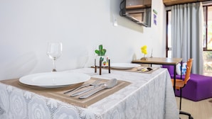 A dining table set with white plates, cutlery, and a glass. A cactus and a yellow flower are on the table.