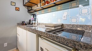 A kitchen with granite countertops, white cabinets, and a backsplash with blue and white tiles.