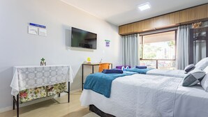 A hotel room with a bed, a desk, a TV, and a window with curtains.