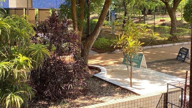 A landscaped area with a pathway, trees, and a signboard.