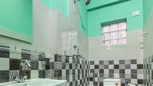 Ein Badezimmer mit Waschbecken, Toilette und Dusche. Die Wände sind mit einem Schachbrettmuster gefliest.