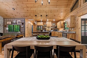 A modern kitchen with wooden cabinetry, a central island, and a dining area with a table and chairs.