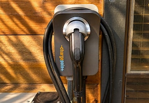 A portable charging station with a cable connected to it, mounted on a wooden surface.