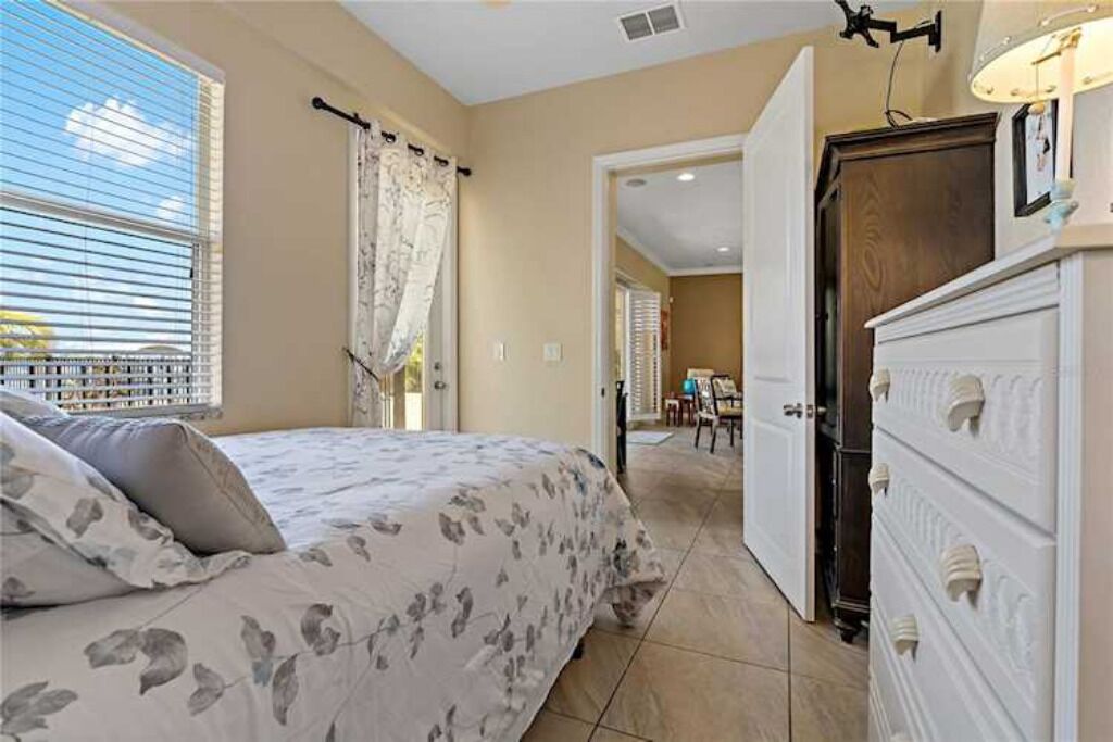 Um quarto com cama, cômoda e porta que dá para outro espaço.