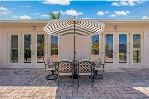 Relax in the shaded patio area with a central table and chairs, surrounded by a patterned umbrella.