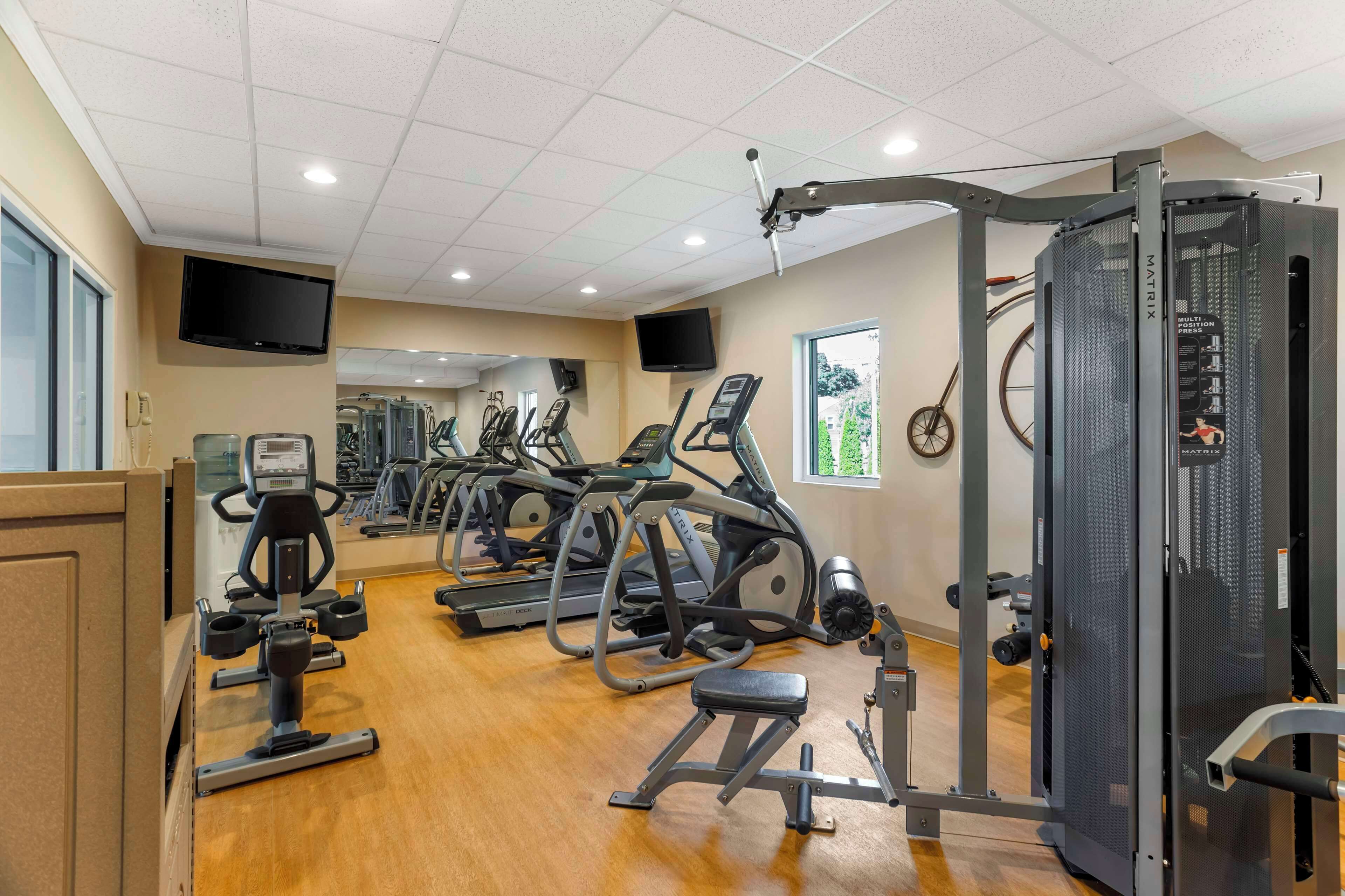 A gym with various exercise equipment, including treadmills, ellipticals, and weight machines.