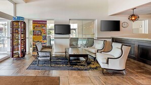 Een moderne lobby met een zithoek, een boekenkast, een flatscreen televisie en een klok aan de muur.