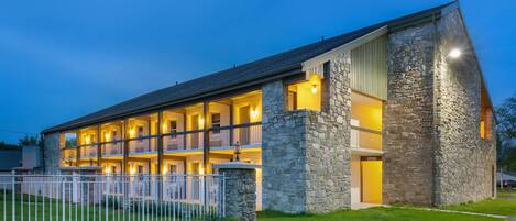 A multi-story hotel with a stone facade, multiple balconies, and a well-lit entrance.