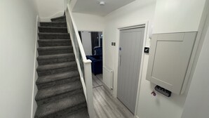 Eine Treppe führt zu einer Zwischenebene mit einer Tür und einem an der Wand befestigten Telefon.