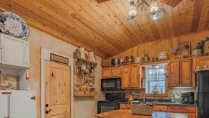A rustic kitchen with wooden cabinets, a central island, and a vintage refrigerator.