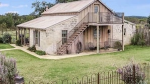 A rustic stone building with a metal staircase leading to a balcony.