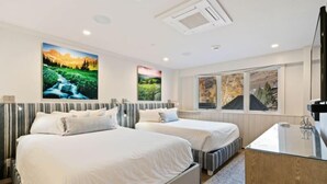Habitación de hotel con dos camas, un ventanal con vistas y un escritorio con espejo.
