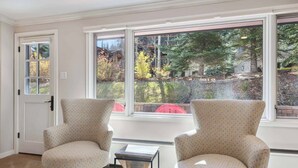 A room with two patterned armchairs, a small table, and a view of trees and a red object outside. - Lodge Tower 199 2BR  at the base of Vail Mountain (Vail)