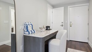 A modern bathroom with a white bathtub, a white vanity with a striped cabinet, and a blue and white striped towel.