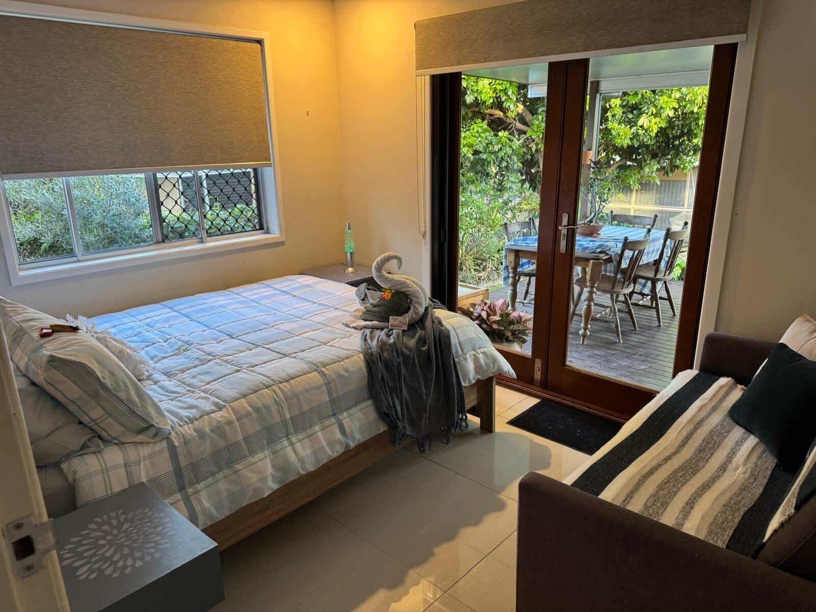 Double bed with air con - wake to peaceful views through french doors across the deck, back yard and park beyond.