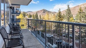 Un balcon avec des chaises et une vue sur les montagnes et les arbres.