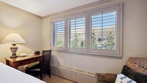 Une chambre d’hôtel équipée d’un bureau, d’une chaise et offrant une vue sur un paysage montagneux par la fenêtre.