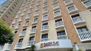 A multi-story building with a flat facade, balconies, and a sign for 'Classic Flat Residence Service'.