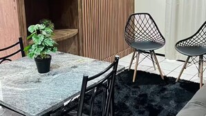 A modern living room with a dining table, two chairs, a sofa, a TV, and a potted plant.