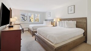 A hotel room with two beds, a desk, a TV, and a window with a view of buildings. - Lodge Tower 491  at the base of Vail Mountain (Vail)
