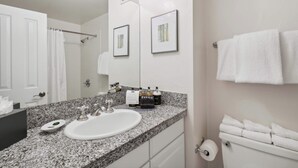 A bathroom with a granite countertop, white sink, and a toilet. There are framed pictures on the wall and a towel rack with towels. - Lodge Tower 491  at the base of Vail Mountain (Vail)