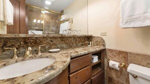 Une salle de bain avec un lavabo en marbre, des meubles en bois et un grand miroir.