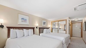 A hotel room with two beds, a large mirror, and framed artwork on the walls.