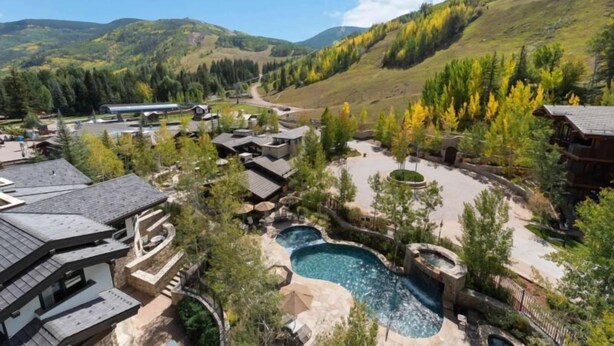 Un resort con varias construcciones, una amplia piscina al aire libre y un pintoresco telón de fondo montañoso.