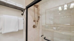 A modern bathroom with a glass-enclosed shower, a toilet, and a towel rack with multiple towels. - Lodge Tower 690  at the base of Vail Mountain (Vail)