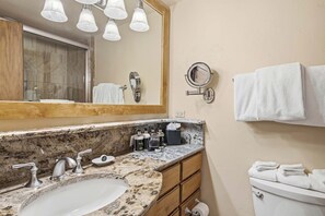Ein Badezimmer mit Granitwaschtisch, Waschbecken, Spiegel, Handtuchhalter und Toilette.