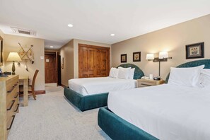 A hotel room with two beds, a desk, a chair, and a wardrobe.