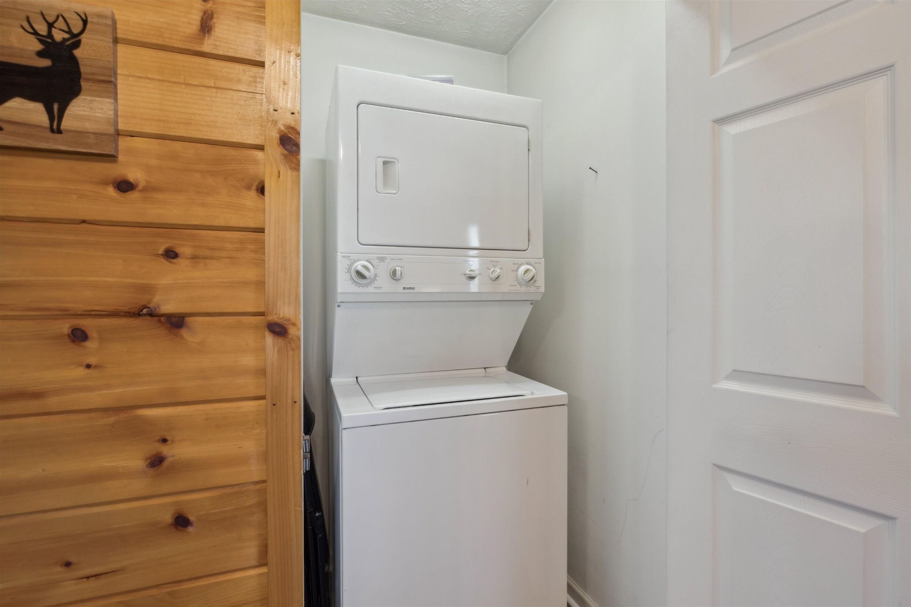 Une buanderie équipée d’un lave-linge et d’un sèche-linge, avec un lambris en bois et une porte.