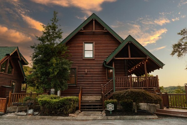 A rustic log cabin with a balcony and a porch, surrounded by greenery and a scenic view. - Amazing Views w Gameroom Hot Tub Pool (Sevierville)