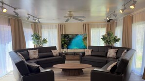 A modern living room with two black sofas, a wooden coffee table, and a ceiling fan.