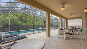 Ein überdachter Außenbereich mit Pool, Liegestühlen und einem Tisch.