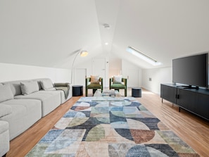 Relax in this spacious living area with a comfortable sofa, armchair, and large flat-screen TV.