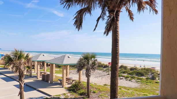 Une vue sur la plage avec un kiosque, des palmiers et une plage de sable.