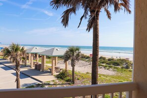 A beach view with a gazebo, palm trees, and a sandy beach.