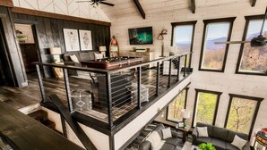 Amplio espacio tipo loft con mesa de billar, un área de descanso acogedora y grandes ventanales con vistas a la montaña.