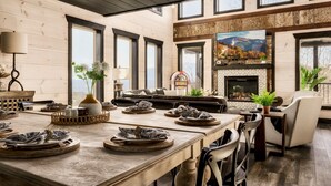 Un amplio salón con una gran mesa de comedor preparada para una comida, una chimenea y un televisor montado en la pared.