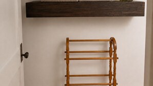 Ein Zimmer mit drei Holzböden, einem gewebten Korb, gerollten Handtüchern, einer Vase mit Blumen und einem Wäscheständer aus Holz.