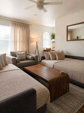 Une chambre d’hôtel moderne comprenant un canapé, une table basse en bois, un lampadaire, une fenêtre avec des rideaux, une plante et un miroir mural.
