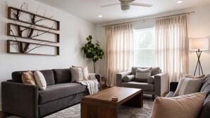 Ein Wohnzimmer mit einer Couch, einem Sessel, einem Couchtisch und einer Pflanze.